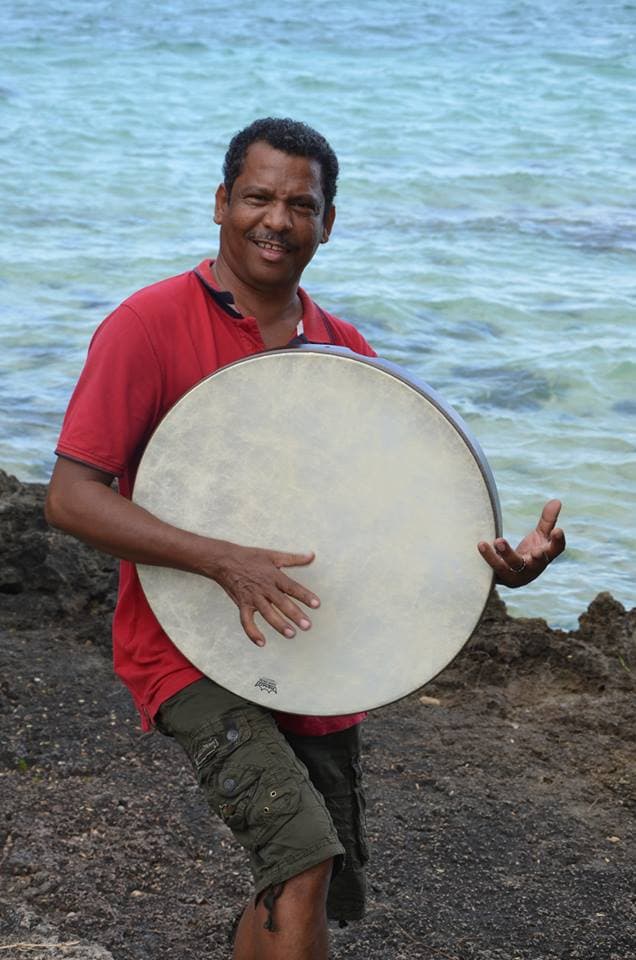 Désiré François, lead singer of Cassiya, holding a ravanne beside the sea