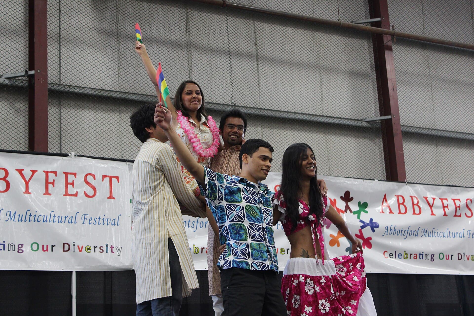 Mauritian performers holding flags during a finale at AbbyFest in Abbotsford