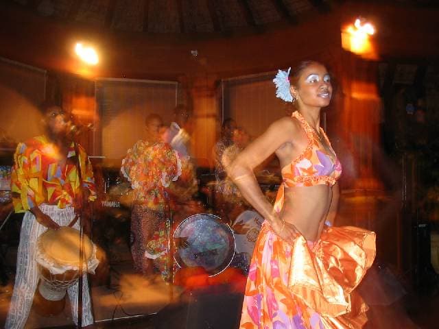 Sega dancer in a floral dress with accompanying musicians at Pointe aux Piments